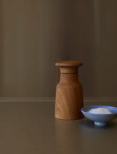 Cargar imagen en el visor de la galería, Wooden salt grinder and a small blue bowl with salt on a brown surface.