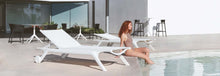 Charger l'image dans la galerie, Woman sitting on a white lounge chair by a pool with modern architectural background