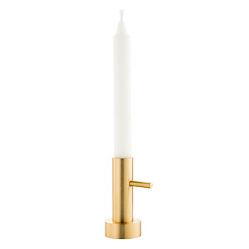 Brass candle holder with a white candle on a white background