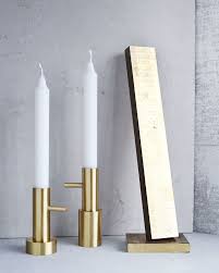 Two white candles in gold candle holders with a mirror on a gray surface.
