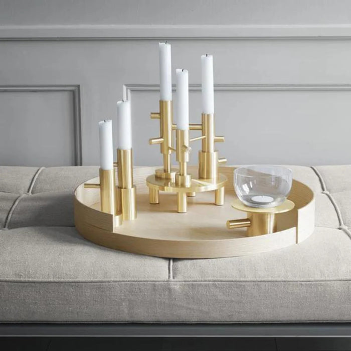 Decorative brass candle holder with white candles on a gray sofa