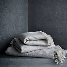 Cargar imagen en el visor de la galería, Folded gray blanket on a dark surface with a dark background
