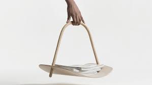 Hand holding a wooden basket with books on a white background