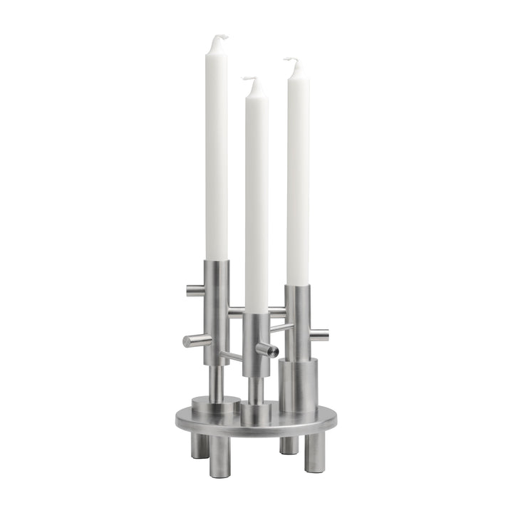 Metallic candle holder with three white candles on a white background