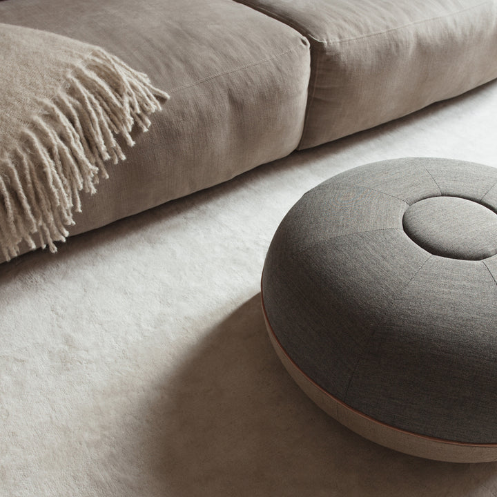 Gray ottoman next to a beige sofa with a blanket