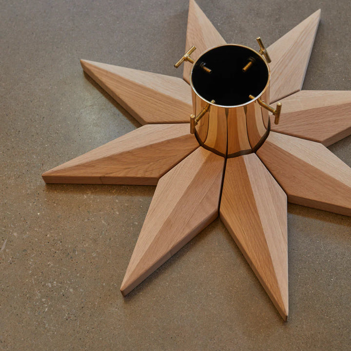 Wooden star-shaped object with a central cylindrical component on a gray surface