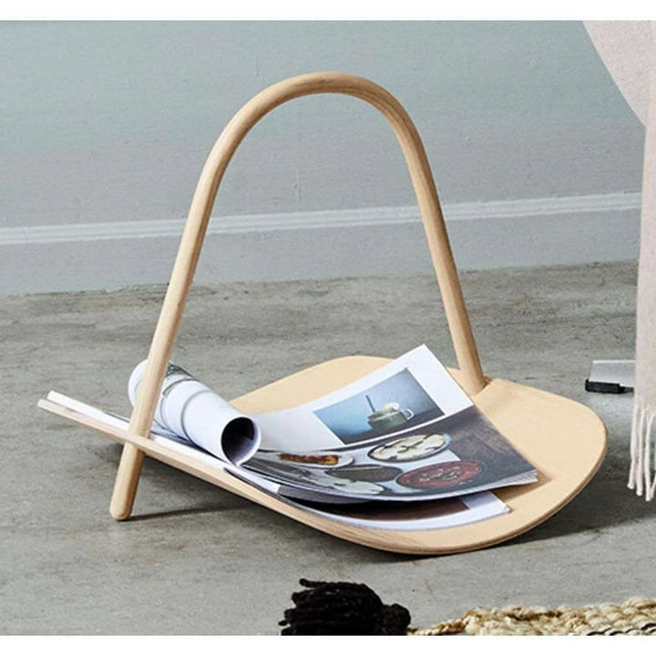 Wooden magazine holder with magazines on a gray floor.