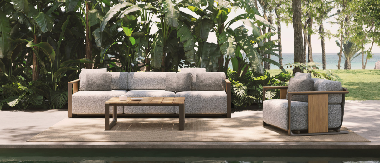 Outdoor patio set with sofa and chair by a poolside, surrounded by greenery.