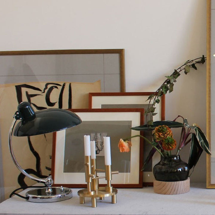 Decorative items including a black lamp, gold candle holder, and vase with flowers on a surface.
