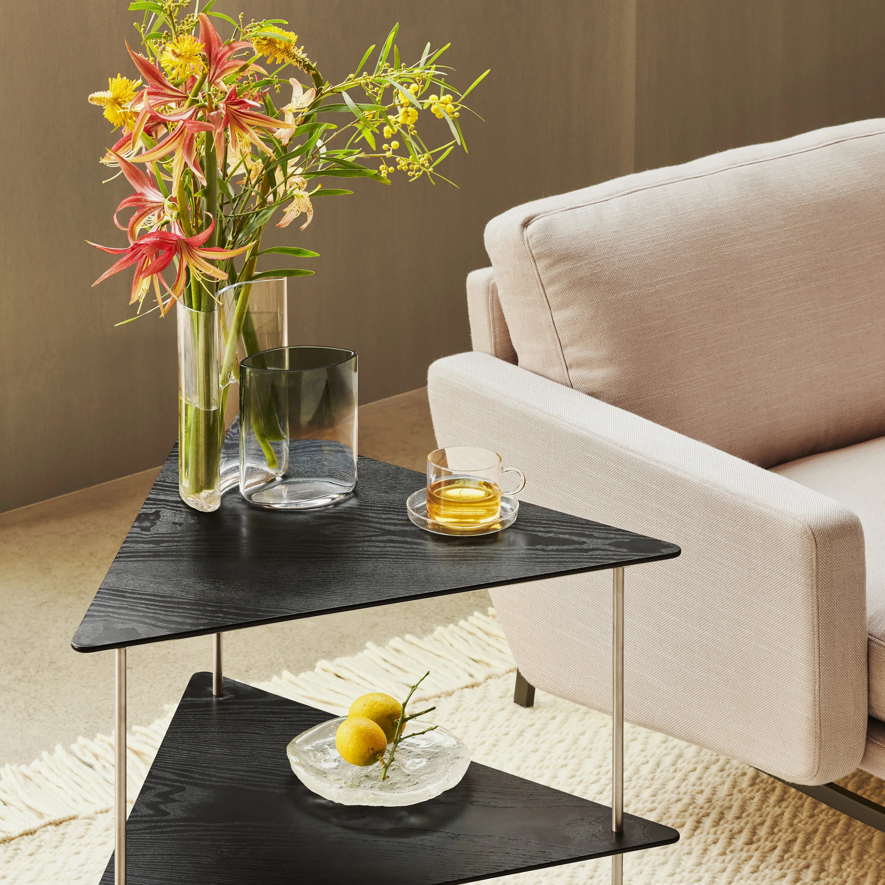 Modern living room with a black side table, flowers, and a glass of tea.