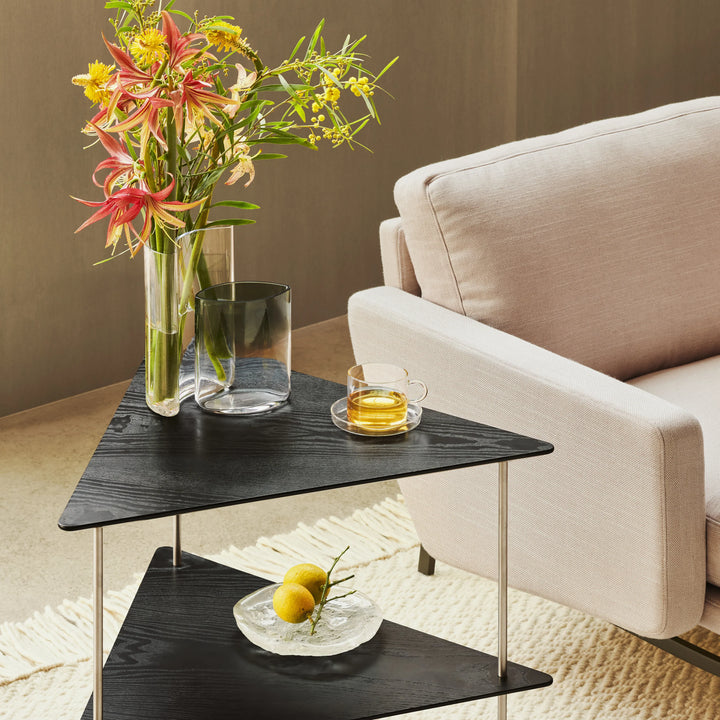 Modern living room with a black side table, flowers, and a glass of tea.