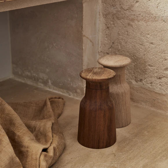 Two wooden stools against a textured wall and floor.