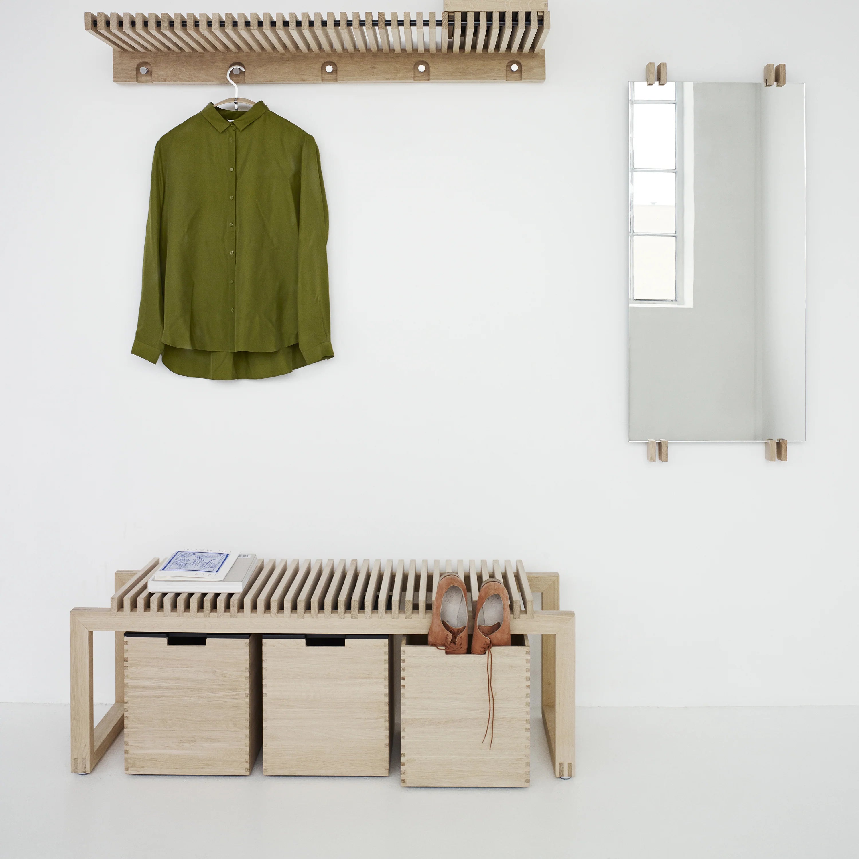 Green shirt hanging on a rack above a wooden bench with storage bins.