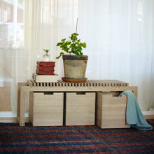Cargar imagen en el visor de la galería, Wooden bench with storage compartments, books, and a plant in a room with white curtains.
