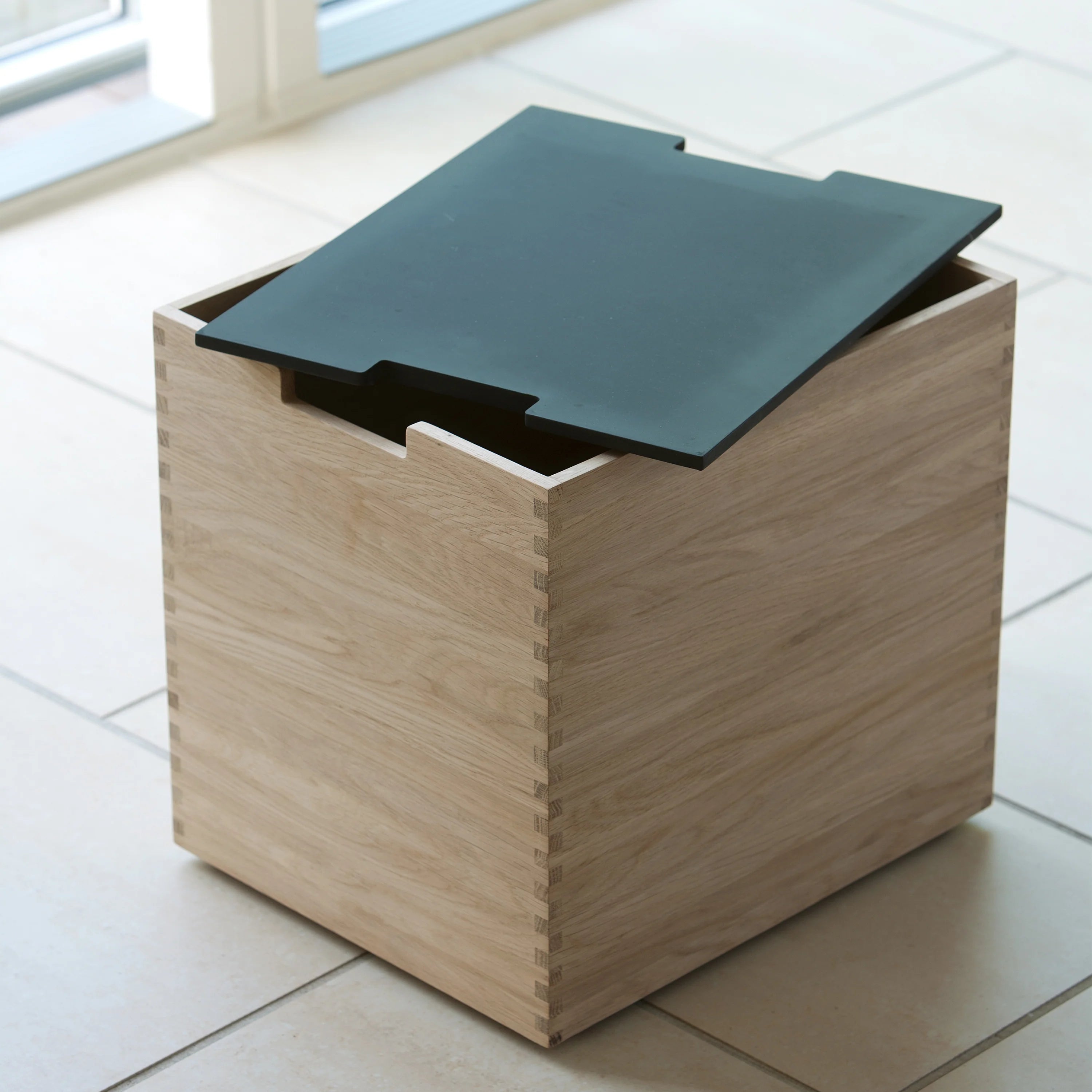 Wooden storage box with a green lid on a tiled floor