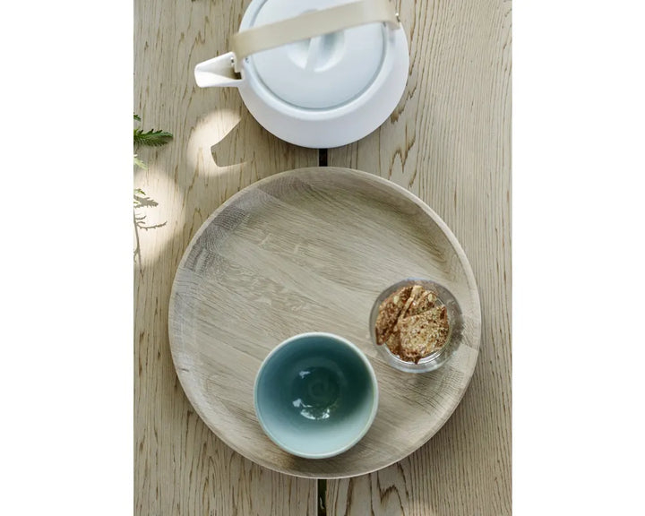 Tea set with a teapot, cup, and small bowl on a wooden tray.