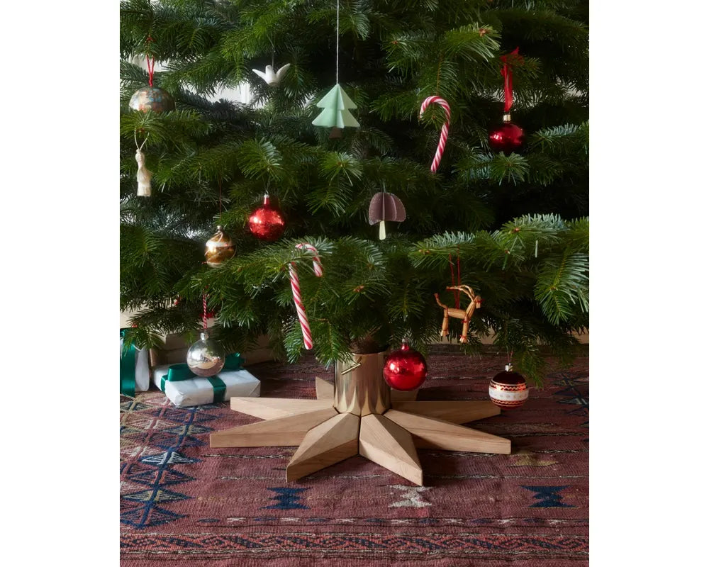 Decorated Christmas tree with various ornaments on a star-shaped stand.