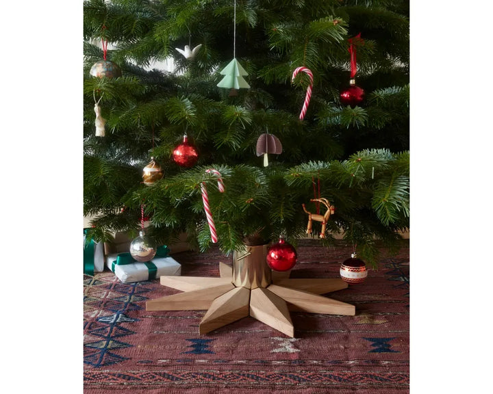 Decorated Christmas tree with various ornaments on a star-shaped stand.